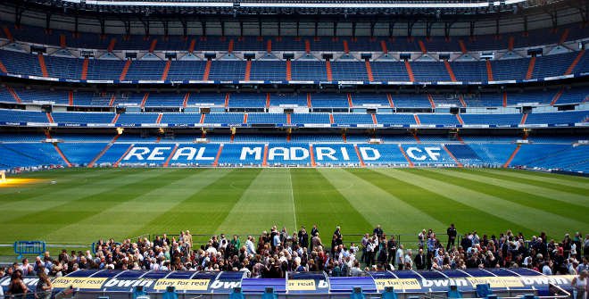 View of the Santiago Bernabéu Stadium, home of Real Madrid CF, with fans gathered near the pitch.