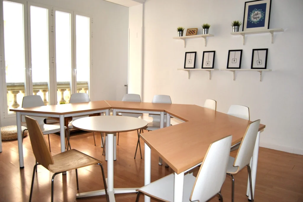 Modern classroom with natural light, wooden floors, white chairs, and decorative shelves at BLC Spain.