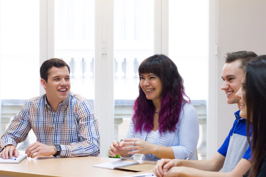 International students smiling and collaborating during a business class at BLC Spain in Madrid.