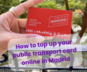 Hand holding a red Madrid public transport card (tarjeta transporte público) with trees in the background.