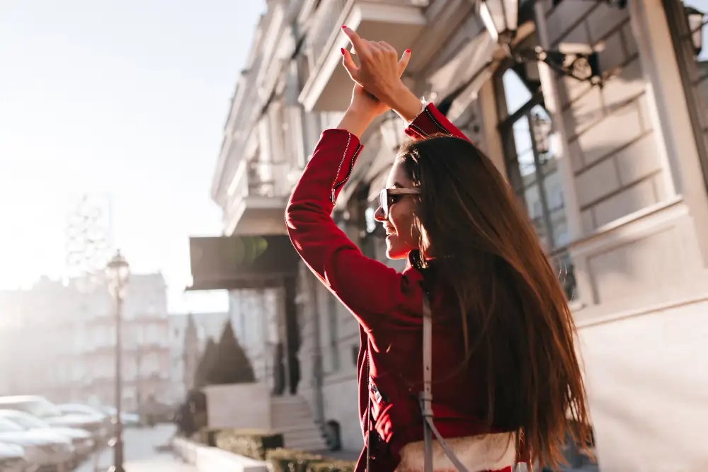 A professional woman in a red jacket expressing joy on a sunny Madrid street, representing the "Balanced Ambition" of BLC Spain.