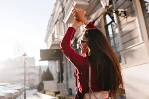 A professional woman in a red jacket expressing joy on a sunny Madrid street, representing the "Balanced Ambition" of BLC Spain