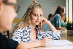 A student sitting at a bright desk holding a pencil, focused on creating her study plan for a Master's degree in Madrid.