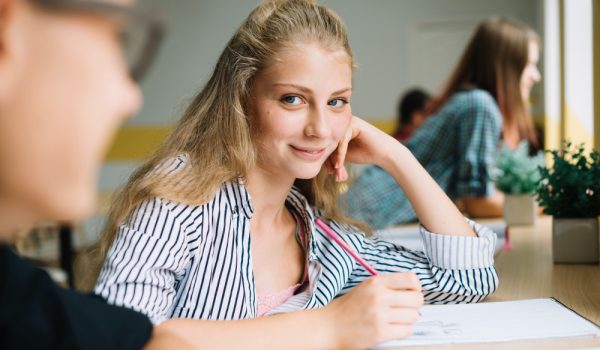 A student sitting at a bright desk holding a pencil, focused on creating her study plan for a Master's degree in Madrid.