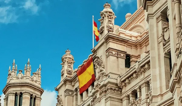 Historic white stone building with Spanish flag in Madrid under a blue sky