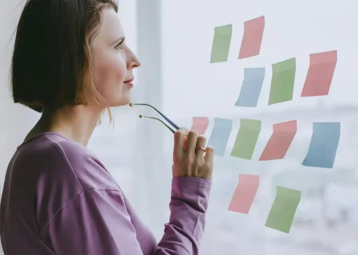 Professional consultant at BLC Spain planning an AI ethics and governance framework using colorful notes on a glass wall.