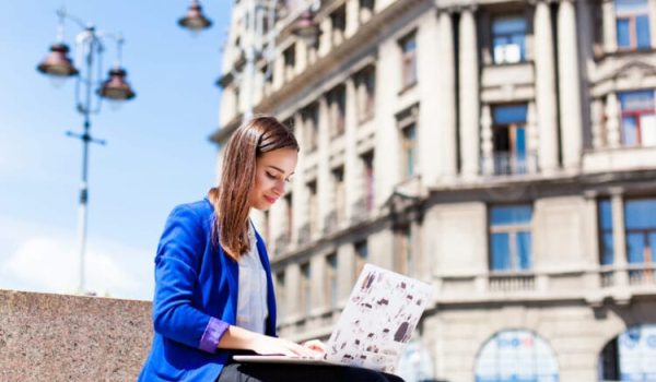 Woman sits on the street and works with a laptop